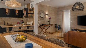 Una cocina moderna con armarios oscuros, encimera de madera y un comedor con sillas de mimbre y una mesa de madera.
