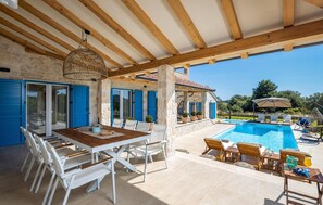 A covered outdoor area with a pool, dining table, chairs, and umbrellas. - Luxurious home in Ugljan with sauna (Ugljan)
