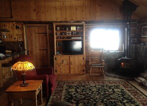 Cozy living room with a stone fireplace, comfortable armchair, and mounted TV.