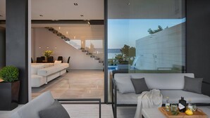A modern interior with a glass wall, a staircase, and a seating area with a tray of drinks.