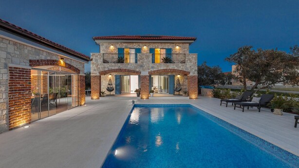 A two-story stone house with a swimming pool, outdoor seating, and a well-lit entrance. - Beautiful home in Sukosan with WiFi (Sukosan)