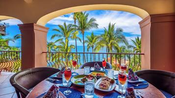 Une table à manger dressée avec des assiettes, des verres et une vue sur un paysage tropical.