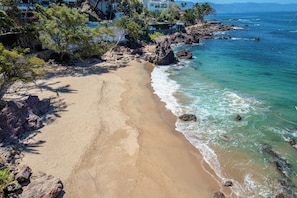 Une plage à l’eau turquoise et limpide, bordée d’une côte rocheuse et d’une végétation luxuriante.