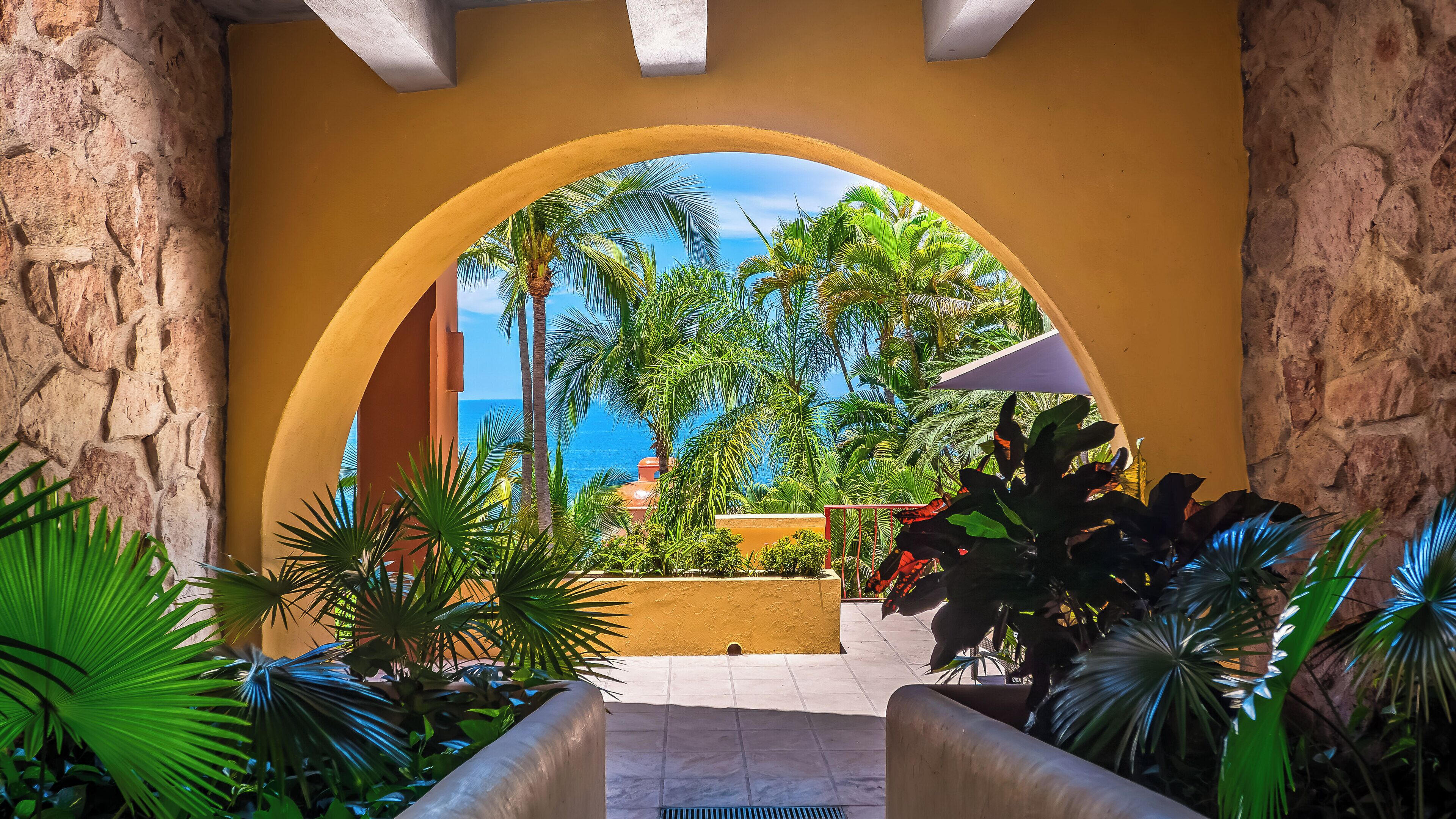 Une entrée en arc offrant une vue sur la mer et sur une végétation tropicale.