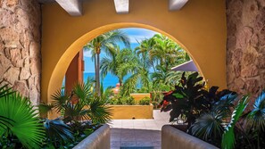 Une entrée en arc offrant une vue sur la mer et sur une végétation tropicale.
