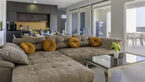 A modern living room with a sectional sofa, a glass coffee table, and a view of the outdoor patio area. - Cozy home in Nin with house sea view (Nin)