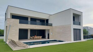 A modern two-story house with a swimming pool, a covered patio, and a well-maintained lawn. - Cozy home in Nin with house sea view (Nin)