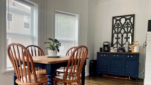 Ein Essbereich mit einem Holztisch und Stühlen, einer Topfpflanze und einem blauen Schrank mit Küchenutensilien.