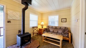 A cozy living room with a fireplace, a sofa, a wooden table, and a lamp. - Big Rock Resort (June Lake)