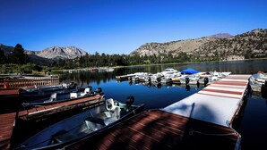 A marina with boats docked, a wooden dock, and a mountain in the background. - Big Rock Resort (June Lake)