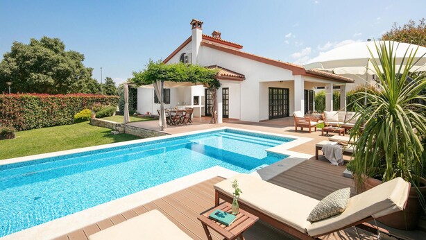 Ein modernes Haus mit Swimmingpool, Gartenmöbeln und Garten.
