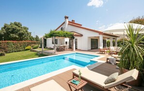 Une maison moderne dotée d’une piscine, de mobilier d’extérieur et d’un jardin.