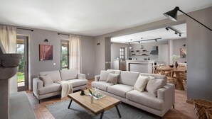 A modern living room with a sofa set, a coffee table, and a dining area with a wooden table and chairs.