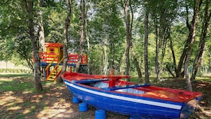 Ein buntes Boot und ein Spielhäuschen in einem bewaldeten Gebiet.