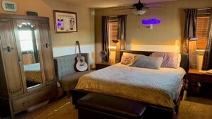 A bedroom with a bed, a bench, a guitar, a clock, and a neon sign. - The Wild West's Best Kept Secret  (Hurricane)