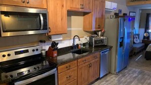 A kitchen with wooden cabinets, a microwave, a stove, a toaster, and a dishwasher. - The Wild West's Best Kept Secret  (Hurricane)