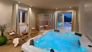 A spa area with a hot tub, wooden lounge chairs, a small table with candles, and a view of an outdoor pool area. - Lovely home in Karojba with sauna (Karojba)