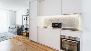 A modern kitchen with white cabinetry, a marble countertop, a built-in microwave, and an oven. - GuestReady - Serene stay in Porto (Porto)