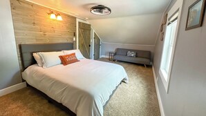 Um quarto com cama, sofá, parede de madeira e ventilador de teto.