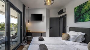 Une chambre d’hôtel moderne équipée d’un lit, d’un bureau, d’une télévision et d’un balcon.