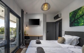 Ein modernes Hotelzimmer mit einem Bett, einem Schreibtisch, einem Fernseher und einem großen Fenster.