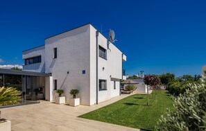 A modern two-story building with a flat roof, satellite dish, and a well-maintained lawn.