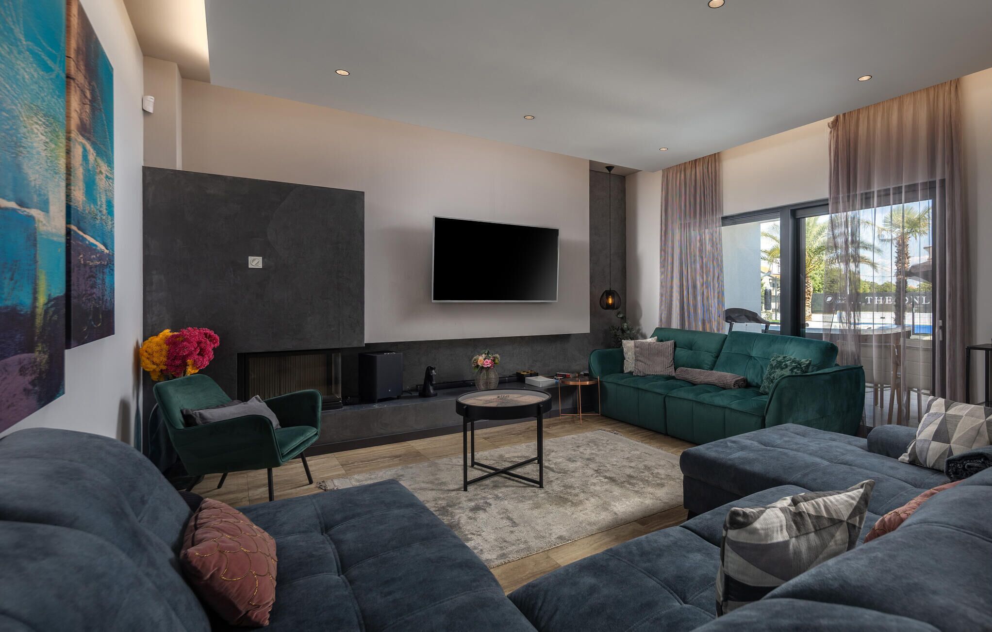 A modern living room with a flat-screen TV, dark sofas, a coffee table, and a fireplace.