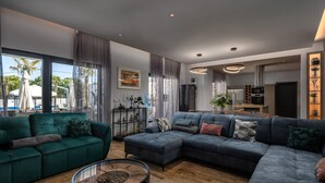 Un salon moderne avec un canapé vert, un canapé d’angle bleu et une table basse ronde.