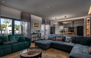 A modern living room with a green sofa, a blue sectional sofa, and a round coffee table.