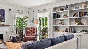 A living room with a leather armchair, a sofa, a bookshelf, and a fireplace.