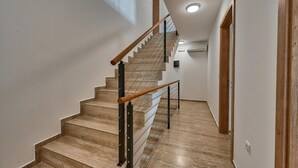 A modern staircase with wooden handrails and a metal railing, leading to a landing with a ceiling light. - 6 bedroom stunning home in Medulin (Medulin)