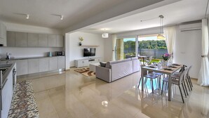 A modern kitchen with a dining area, a sofa, and a view of greenery. - 6 bedroom stunning home in Medulin (Medulin)
