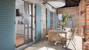 Zona pranzo con tavolo e sedie, vista sulla cucina e parete in mattoni.