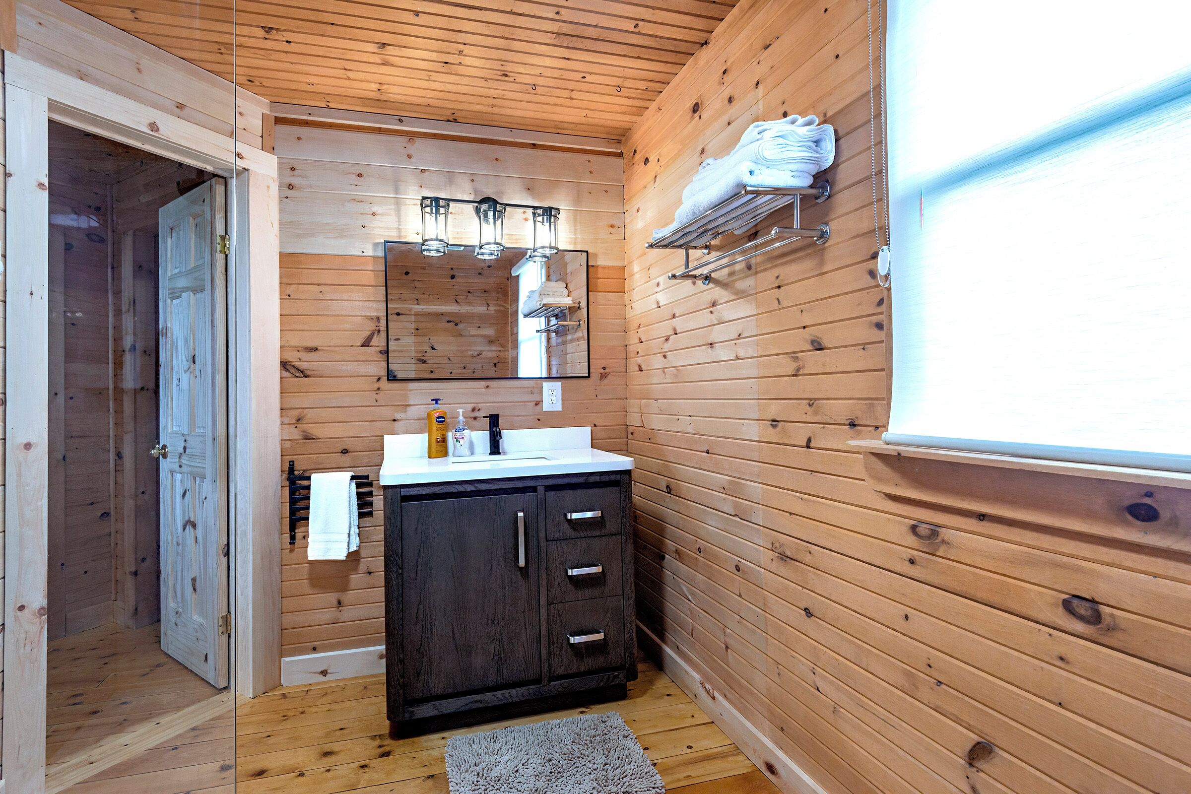 Un bagno con rivestimenti in legno, un lavabo, uno specchio e un porta asciugamani.