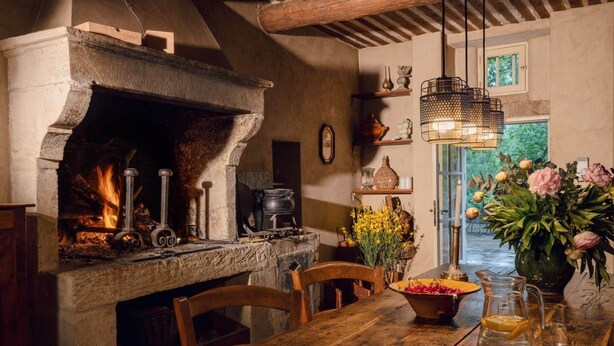 Una cucina rustica con camino in pietra, mobili in legno e vista sul verde circostante.