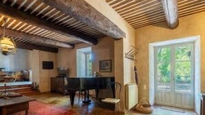 Un'ampia stanza con un pianoforte, un tavolo da pranzo e una grande finestra.