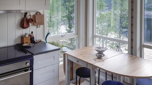 Eine moderne Küche mit großem Fenster, einem Holztisch und zwei blauen Stühlen.