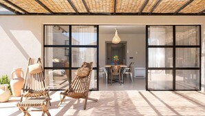 Un espacio de estar abierto con una mesa de comedor, dos sillones de madera y un gran ventanal corredero que da a la cocina.