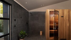 Un baño moderno con ducha, un armario de madera y una planta en maceta.