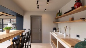 Una cocina moderna con encimeras de madera, un comedor con sillas e iluminación colgante.