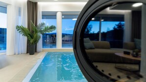 Ein Hallenbad mit Blick ins Freie, eine Sitzecke und ein Blumentopf.