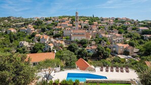 A hillside village with stone buildings, a prominent church, and a swimming pool area. - Amazing home in Lozisca with WiFi (Lozisca)