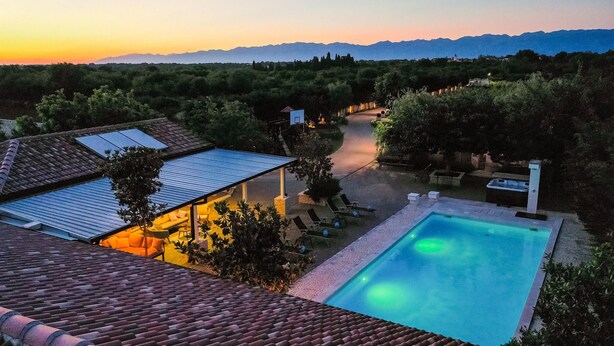 A rooftop pool with a clear view of the surrounding landscape, including a path leading to a building with a sloped roof.
