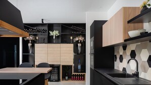 A modern kitchen with a black countertop, wooden cabinets, and a wine rack.