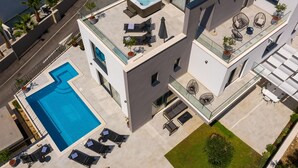 A modern building with a rooftop pool, lounge chairs, and a hot tub.