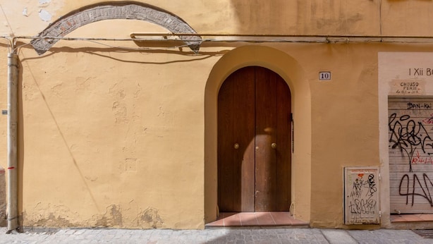 Un bâtiment à la façade jaune, avec une porte en bois et une petite enseigne indiquant le numéro 10.