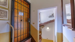 Un escalier avec une rampe en bois, une porte en métal et un mur orné de tableaux encadrés.