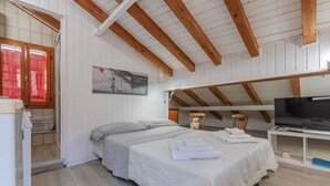 Une chambre à coucher avec un lit, une télévision et une fenêtre avec des rideaux.
