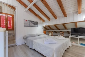 Une chambre à coucher avec un lit, une télévision et une fenêtre avec des rideaux.