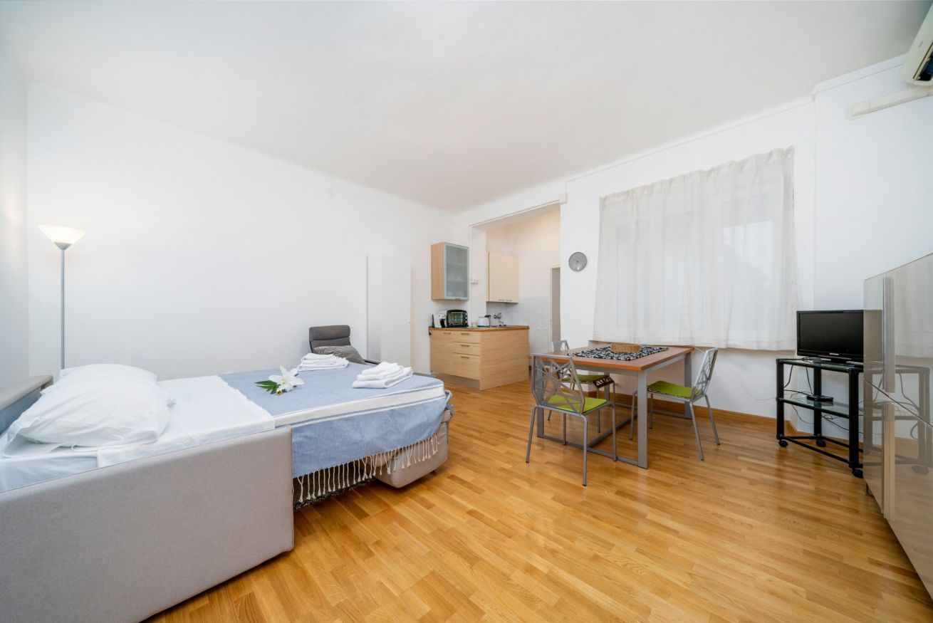 Un dormitorio con cama, escritorio, silla, televisor y armario.